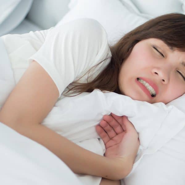 woman suffering from bruxism or teeth grinding in her sleep