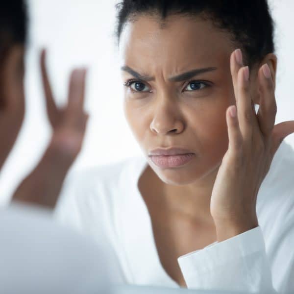 woman worried about skin concerns in the mirror such as ageing or acne