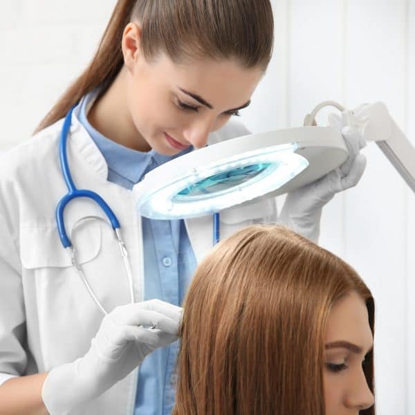 doctor or dermatologist inspects a woman for hair loss